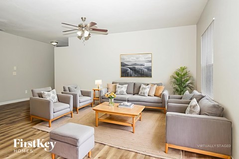 A living room with a grey couch, a coffee table, and a painting on the wall.