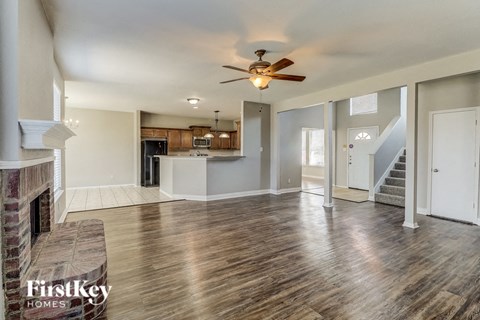 A spacious living room with wood flooring and a fireplace.