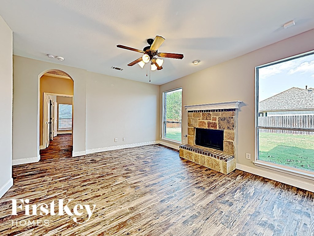 an empty living room with a fireplace and a ceiling fan