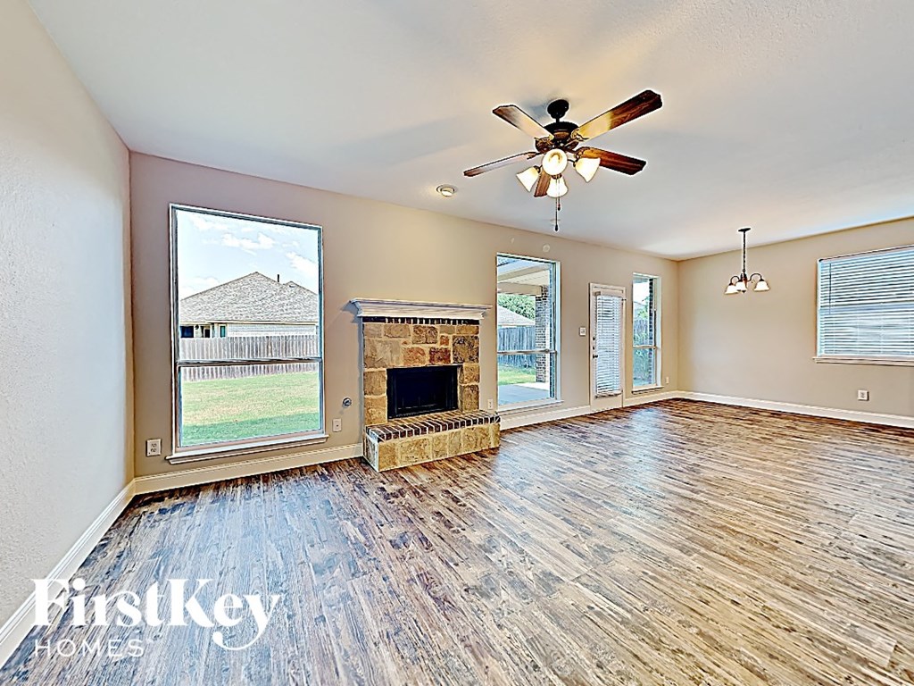 an empty living room with a fireplace and a ceiling fan