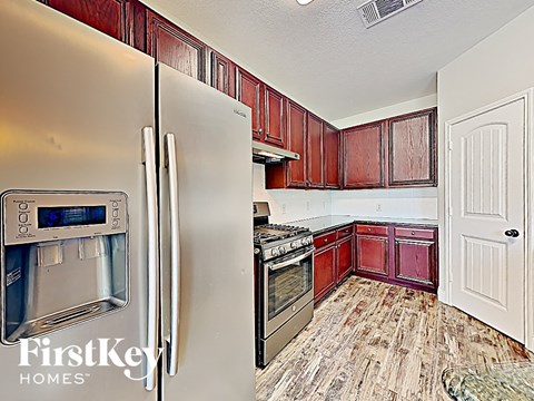 a kitchen with red cabinets and stainless steel appliances and a refrigerator