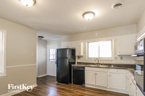 A kitchen with white cabinets and black appliances.