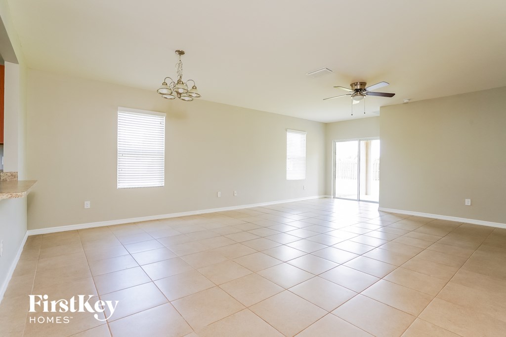 A spacious room with a fan and a chandelier.