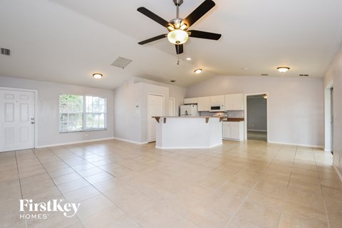 an empty living room and kitchen with a ceiling fan