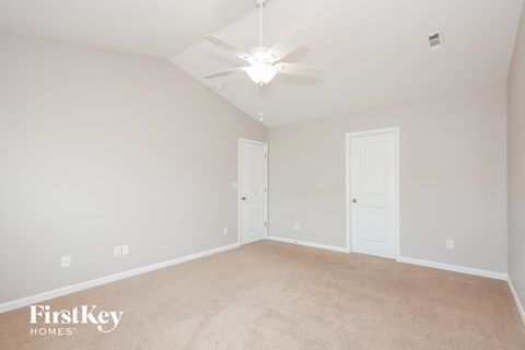 A spacious room with a carpeted floor and a ceiling fan.
