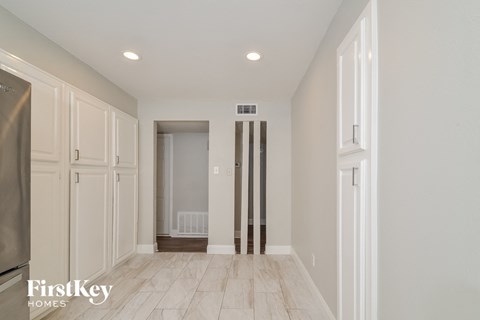 A kitchen with a refrigerator and wooden floors.