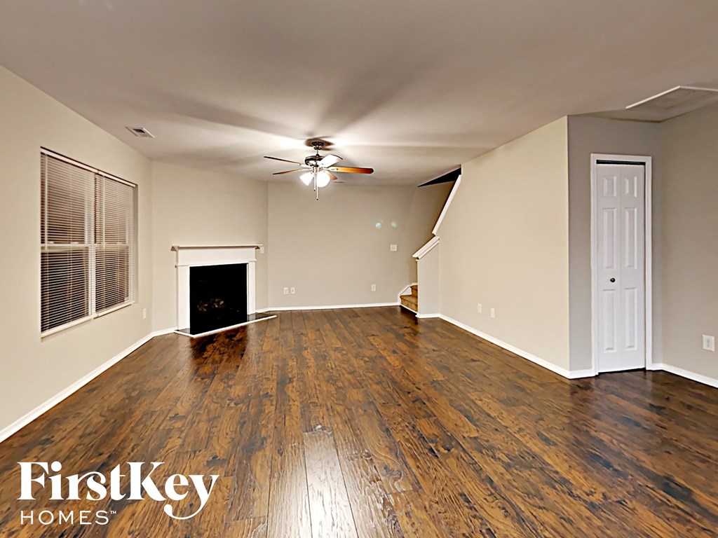 A spacious room with wooden floors and a ceiling fan.