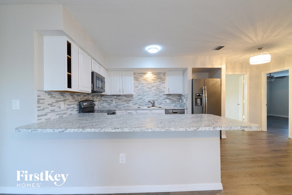 a kitchen with white cabinets and a marble counter top