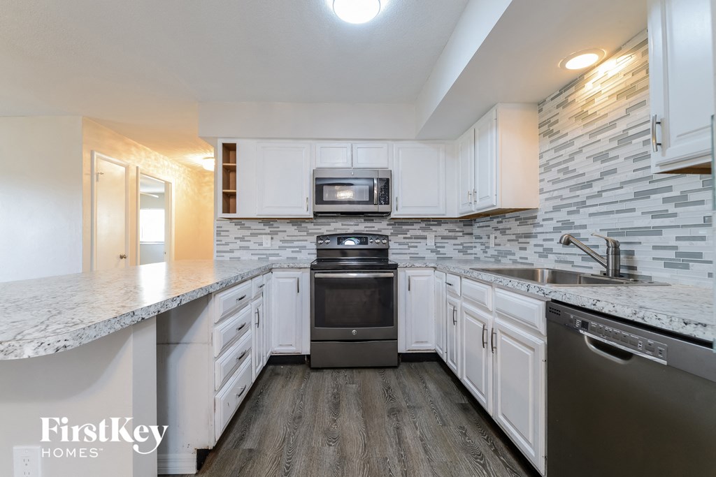a kitchen with white cabinets and stainless steel appliances