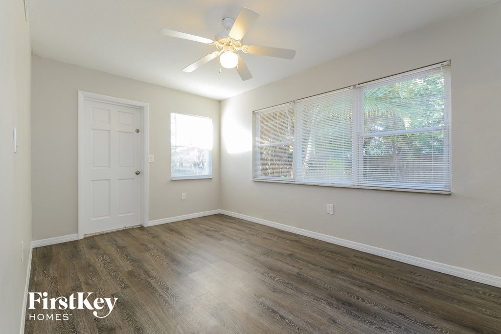 an empty living room with a ceiling fan and a large window