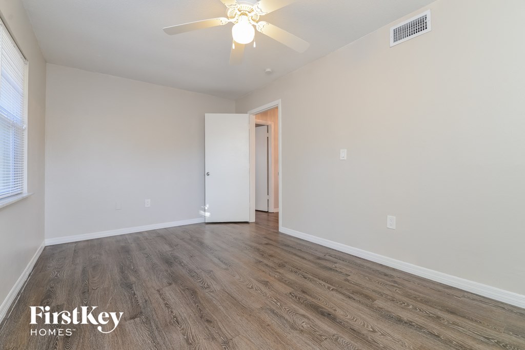the living room of an empty house with wood flooring and a ceiling fan