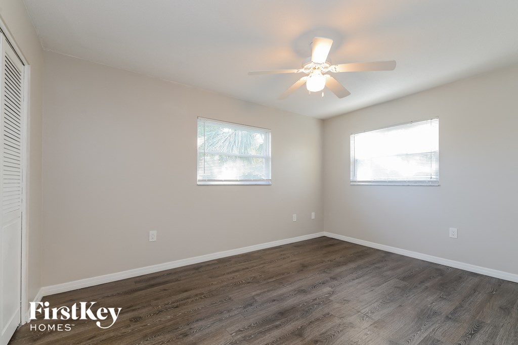 a bedroom with white walls and wood flooring and a ceiling fan