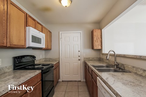 A kitchen with a black stove top oven and a white microwave.