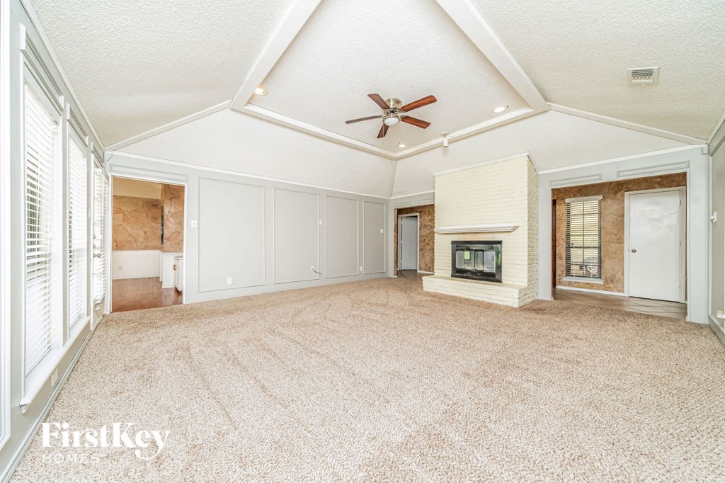 A spacious room with a fireplace and a ceiling fan.