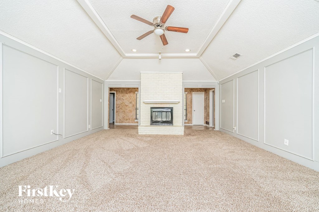 A spacious room with a fireplace and a ceiling fan.