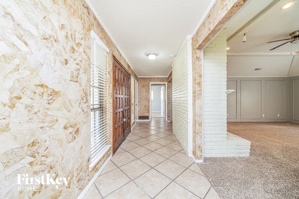 A hallway with a stone wall and a carpeted floor.