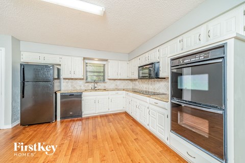 A kitchen with wooden floors and white cabinets.