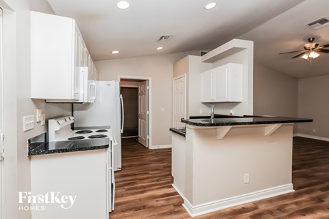 A kitchen with white cabinets and a black countertop is shown.