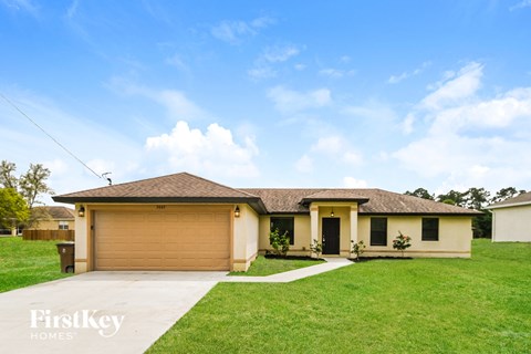 a yellow house with a garage and a green lawn