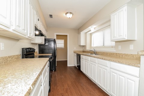 A kitchen with white cabinets and a granite counter top.