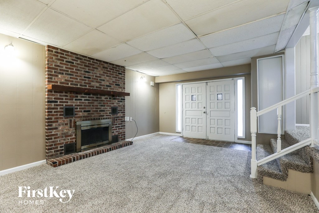 A room with a brick fireplace and a carpeted floor.