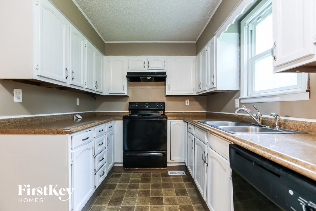 A kitchen with white cabinets and a black oven.