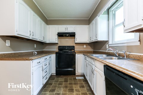 A kitchen with white cabinets and a black oven.