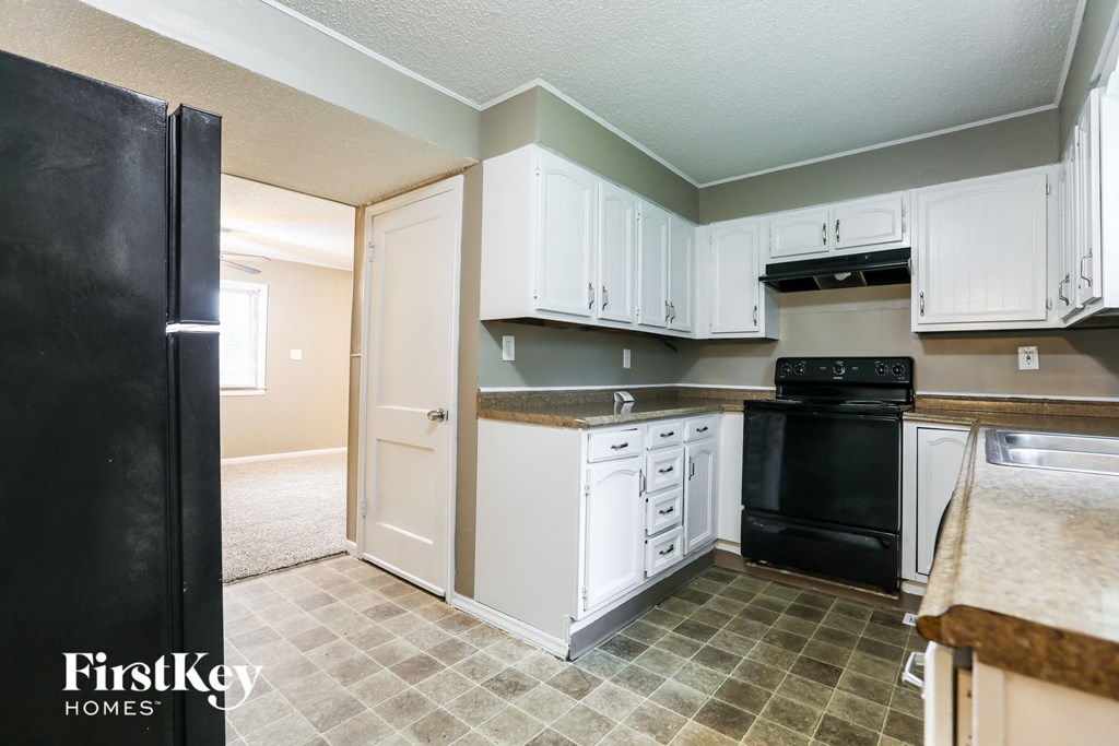 A kitchen with black appliances and white cabinets.