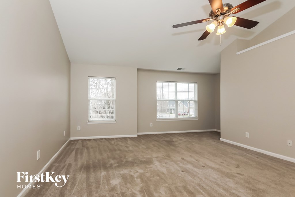 the spacious living room with ceiling fan and hardwood floors