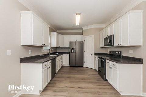 a kitchen with white cabinets and black counter tops and a refrigerator