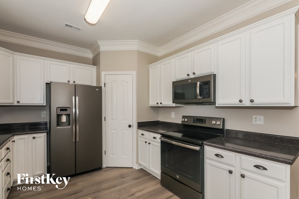 a kitchen with white cabinets and black appliances and a stainless steel refrigerator