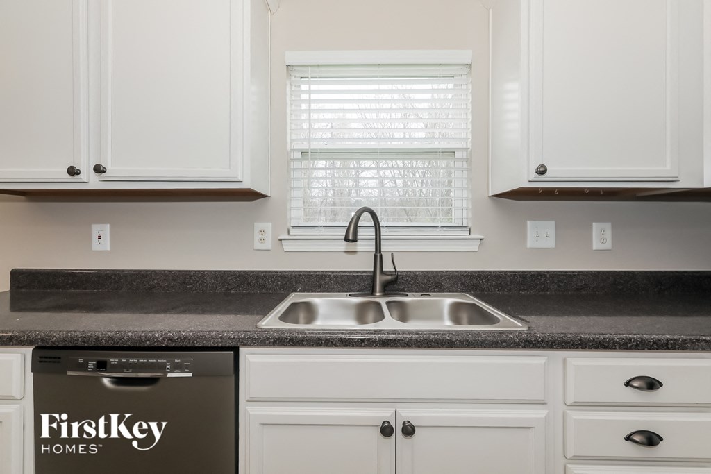 a kitchen with white cabinets and a sink and a window
