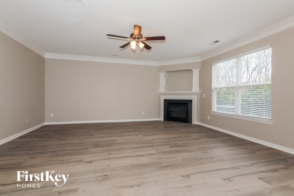 an empty living room with a ceiling fan and a fireplace