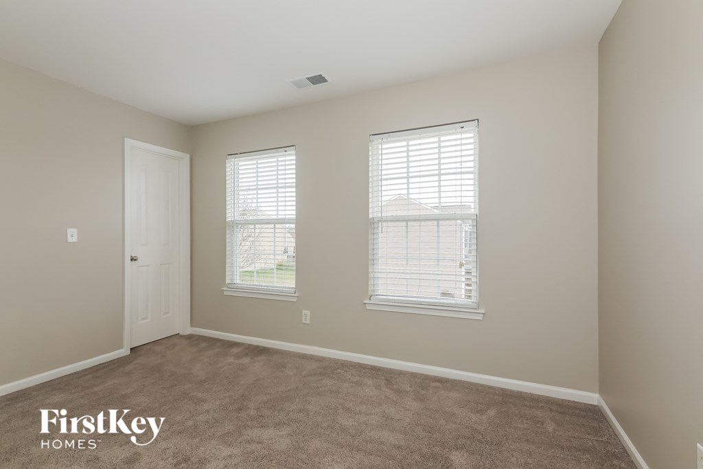 a bedroom with a carpeted floor and two windows