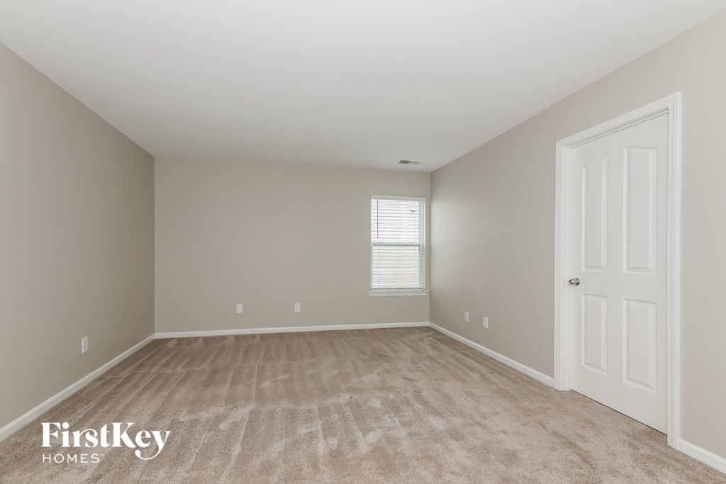 a bedroom with a white door and a carpeted floor