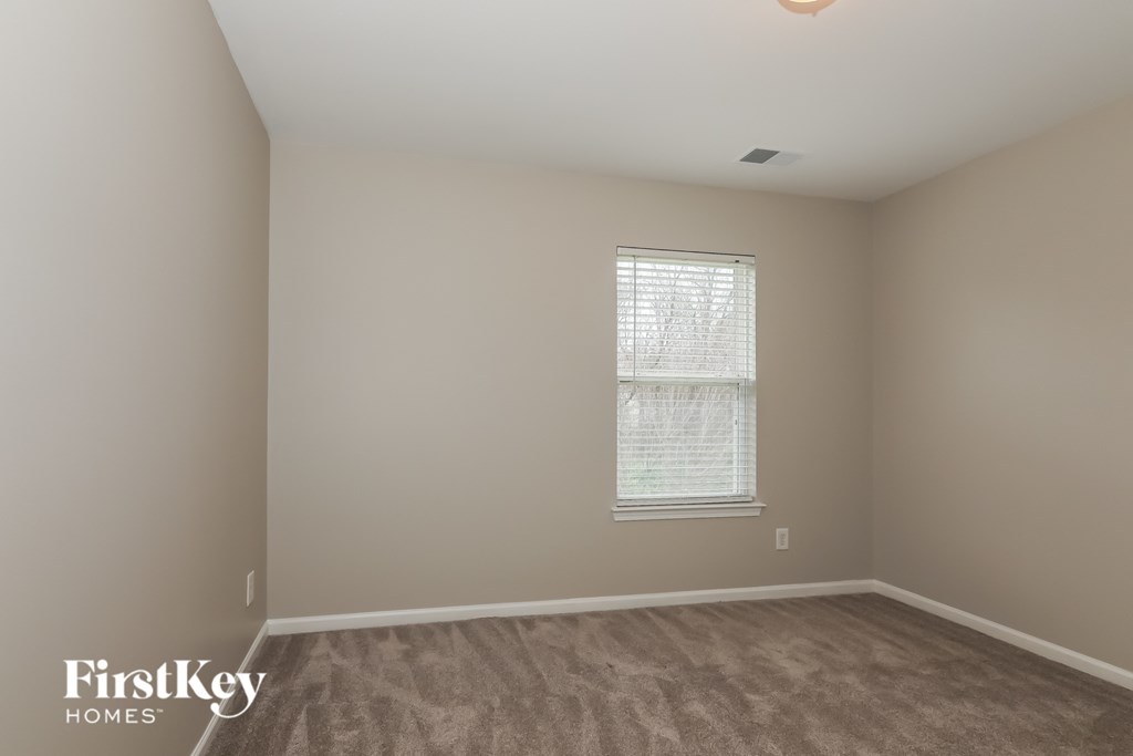 a bedroom with a window and a carpeted floor