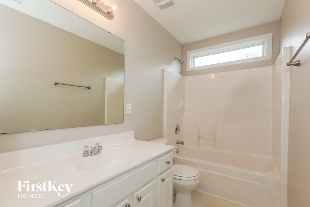 a white bathroom with a tub and a sink and a mirror