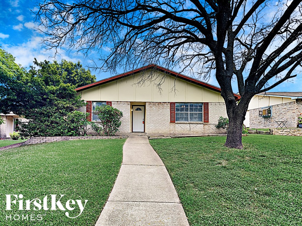a house with a sidewalk and a tree in front of it