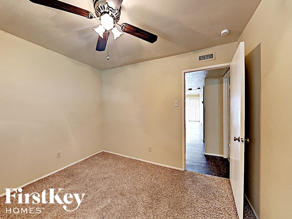 the master bedroom has a ceiling fan and a door to the hallway