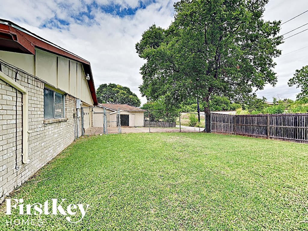 a fenced in backyard with a tree and a fence