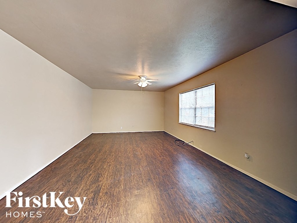 an empty living room with wood floors and a window