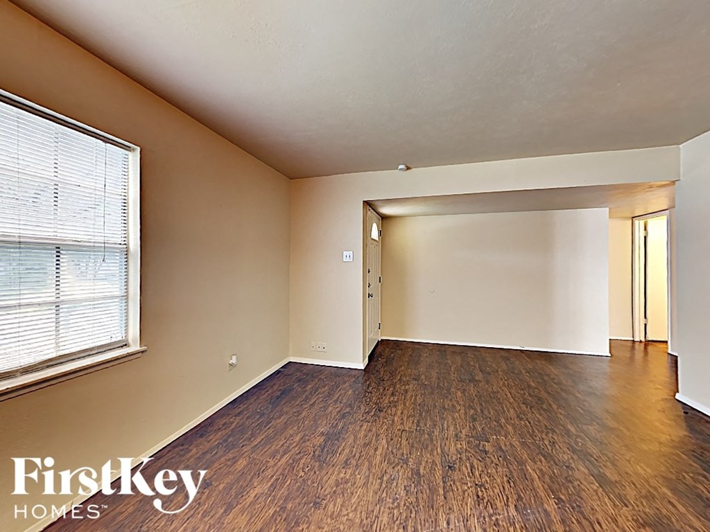 an empty living room with a large window and wood flooring