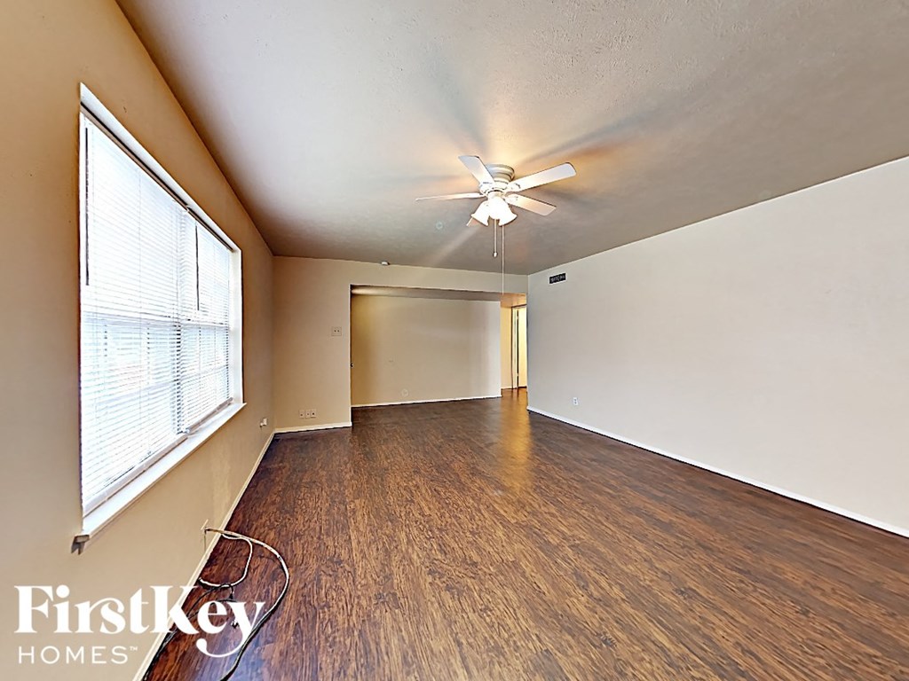 an empty living room with a ceiling fan and a large window