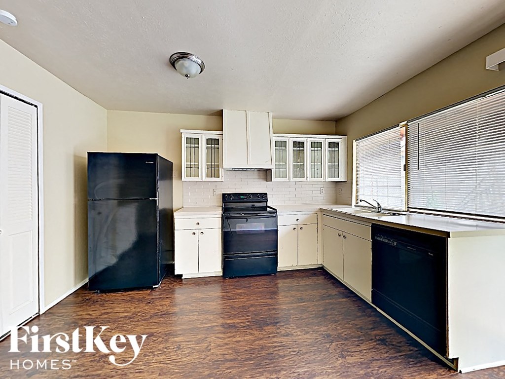 an empty kitchen with black appliances and white cabinets