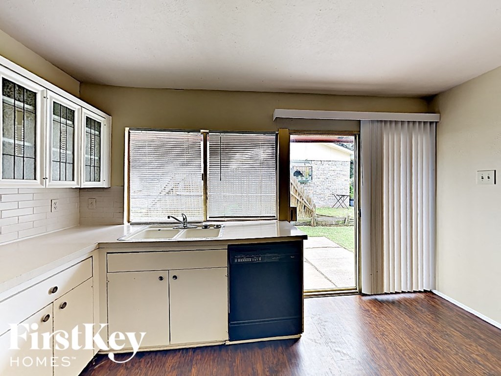 a kitchen with white cabinets and a dishwasher and a sliding glass door