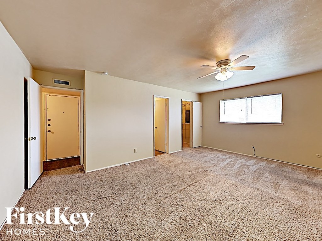the living room of an empty house with a ceiling fan