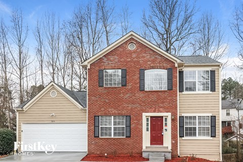 a brick house with a red front door and a white garage