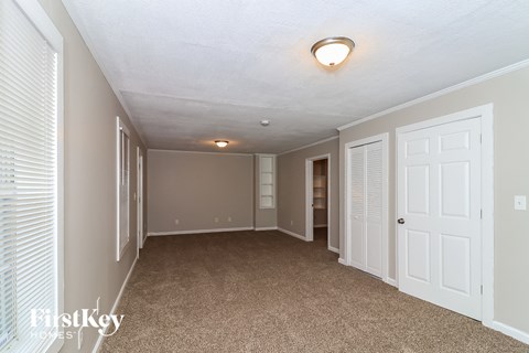 a spacious living room with a carpeted floor and white doors