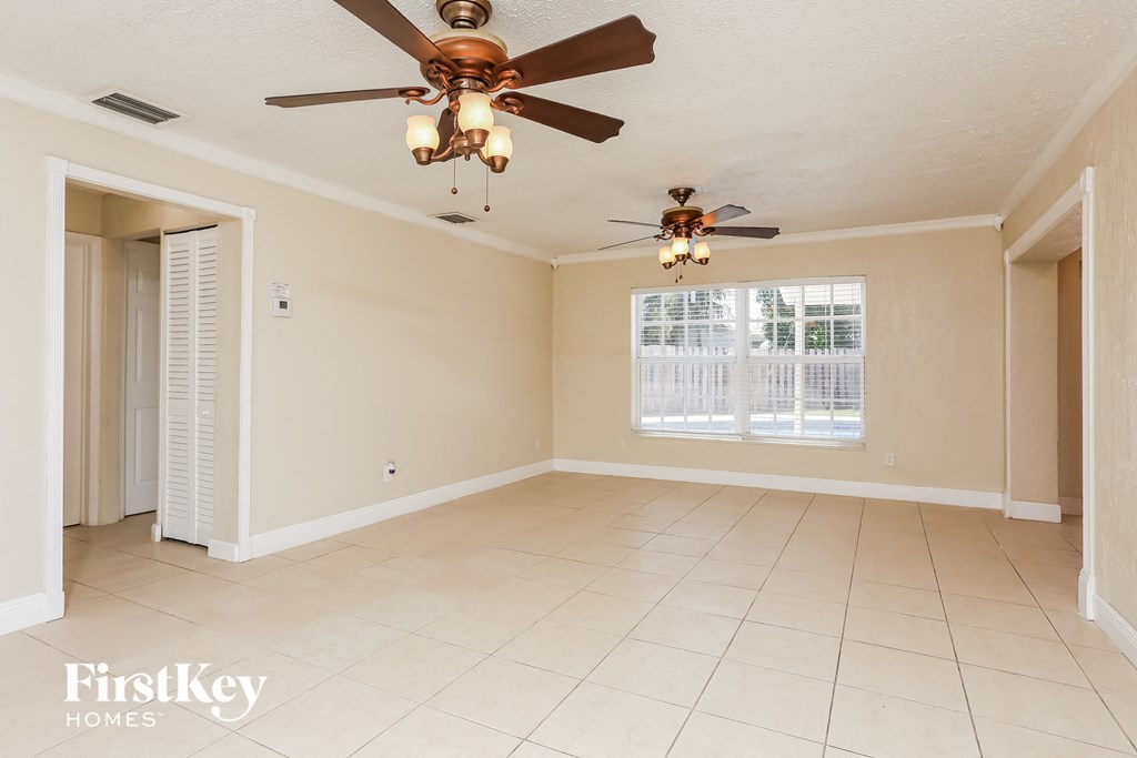 A spacious room with a ceiling fan and tiled flooring.