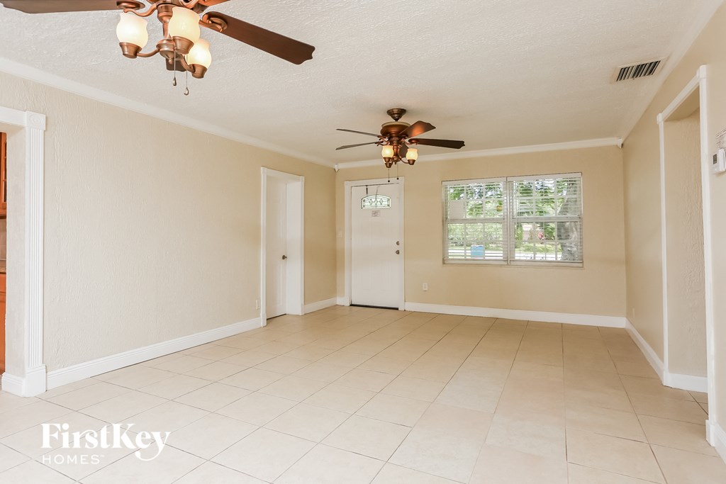 A spacious room with a ceiling fan and tiled flooring.